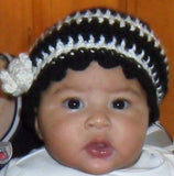 Adorable baby wearing a handmade black and white crochet beanie with flower detail by MALVIA's